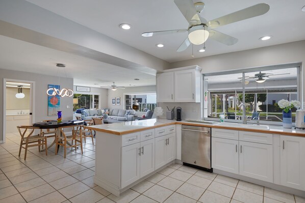 A modern kitchen with white cabinetry, a central island, and a large window. - Waterfront home near beaches, Multi month discount - inquire (Fort Myers)