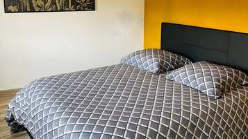 A bedroom with a bed, a headboard, a wall-mounted artwork, and a ceiling light fixture.