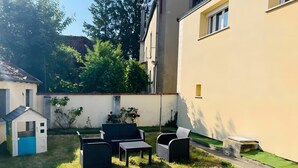 A backyard with a playhouse, outdoor seating, and a small garden. - Gîte Le Flot House with Private Garden and Wi-Fi (Saint-Florentin)