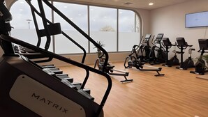 A gym with cardio equipment, a large window, and a mounted TV. - Gîte Le Flot House with Private Garden and Wi-Fi (Saint-Florentin)