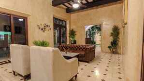 A lobby with a brown leather sofa, two armchairs, a coffee table, and a ceiling fan. - HOTEL RAMI (Valladolid)
