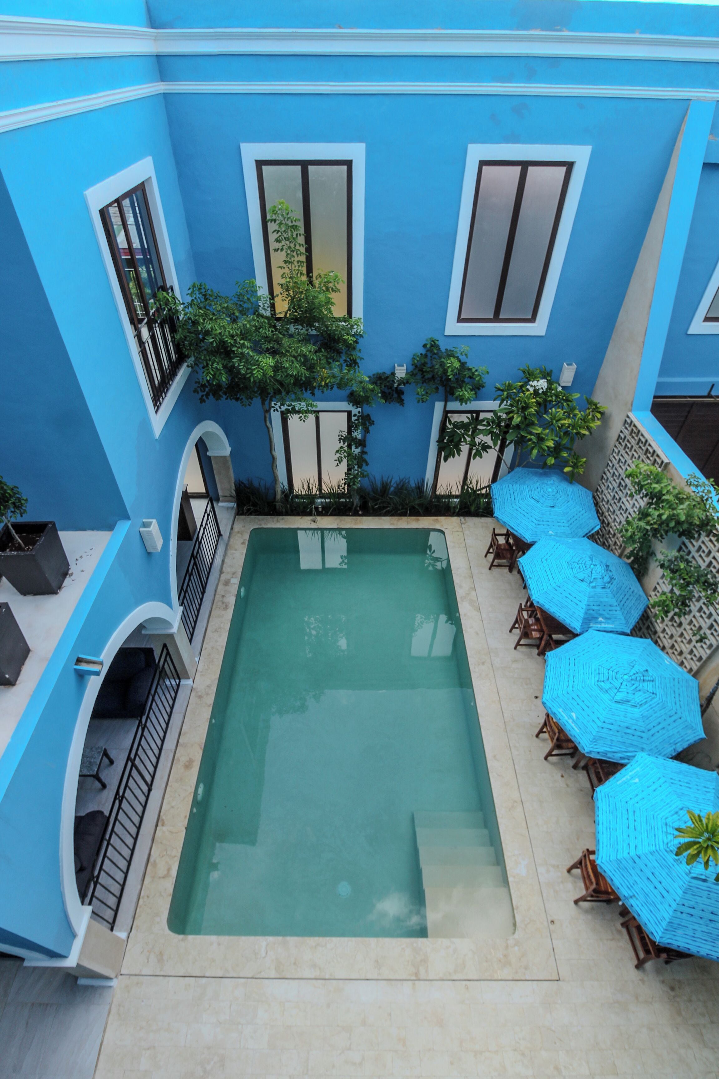 Una piscina en la azotea con paredes azules y una vista despejada del cielo.
