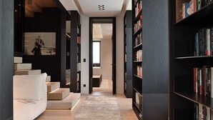 A modern interior with a staircase, bookshelves, and a sofa.