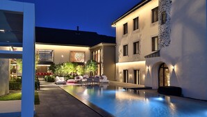 A modern building with a pool, outdoor seating, and a stone facade.