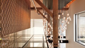 A modern interior with a wooden staircase, glass railings, and a patterned wall.