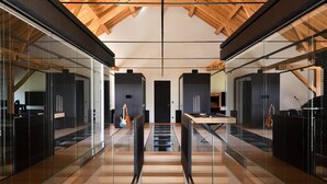 A modern interior with a high ceiling, glass railings, and a central staircase.