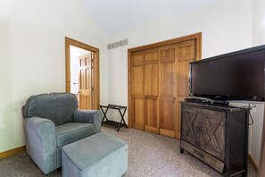 A living room with a grey sofa, a television on a wooden cabinet, and a wooden wardrobe. - The Retreat at Wildcat Hollow (Rockbridge)