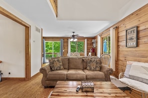 A cozy cabin interior with a wooden interior, a sofa, a coffee table, and a ceiling fan. - The Retreat at Wildcat Hollow (Rockbridge)