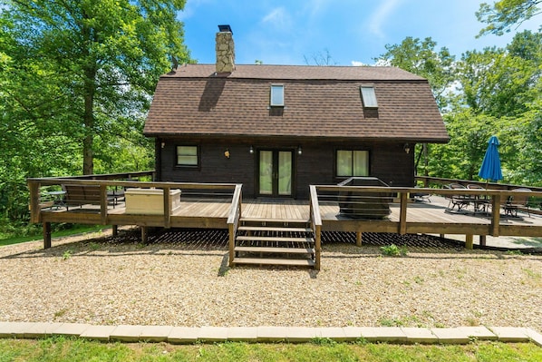 A cabin with a deck, outdoor seating, and a chimney. - The Retreat at Wildcat Hollow (Rockbridge)