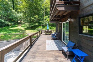 A wooden deck with outdoor seating, a pergola, and a view of a forested area. - The Retreat at Wildcat Hollow (Rockbridge)