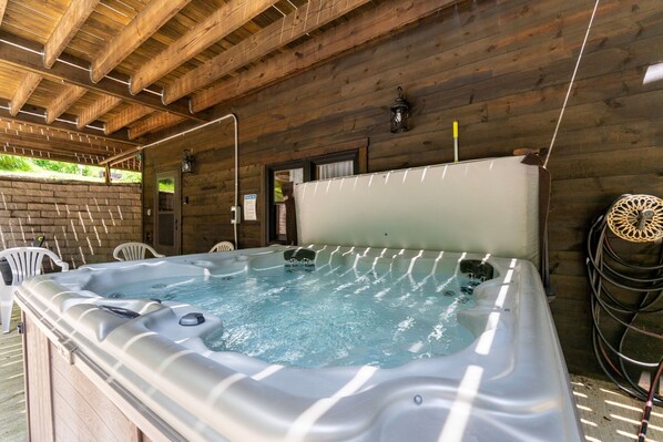 A hot tub in a wooden cabin with a wooden ceiling, a door, and a small window.