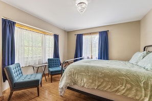 A bedroom with a bed, two chairs, a small table, and a window with curtains. - The Retreat at Wildcat Hollow (Rockbridge)