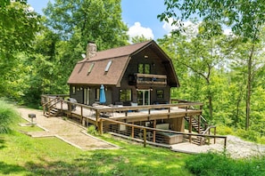 A cabin with a deck, outdoor seating, and a stone chimney. - The Retreat at Wildcat Hollow (Rockbridge)