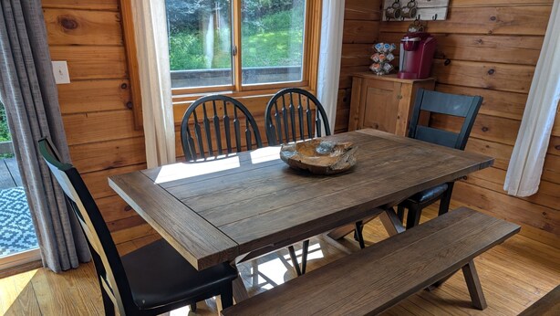 Una mesa de madera con sillas, un banco y un cuenco decorativo.