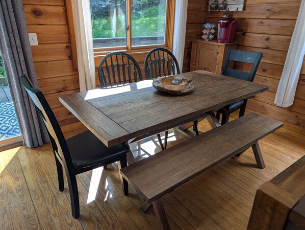 A wooden dining table with chairs, a bench, and a decorative bowl. - The Retreat at Wildcat Hollow (Rockbridge)