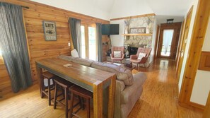 A cabin interior with a wooden dining table, a sofa, and two armchairs.
