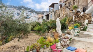 Una propiedad en la ladera con una escalera de piedra, plantas en macetas y vistas a un pueblo al fondo.