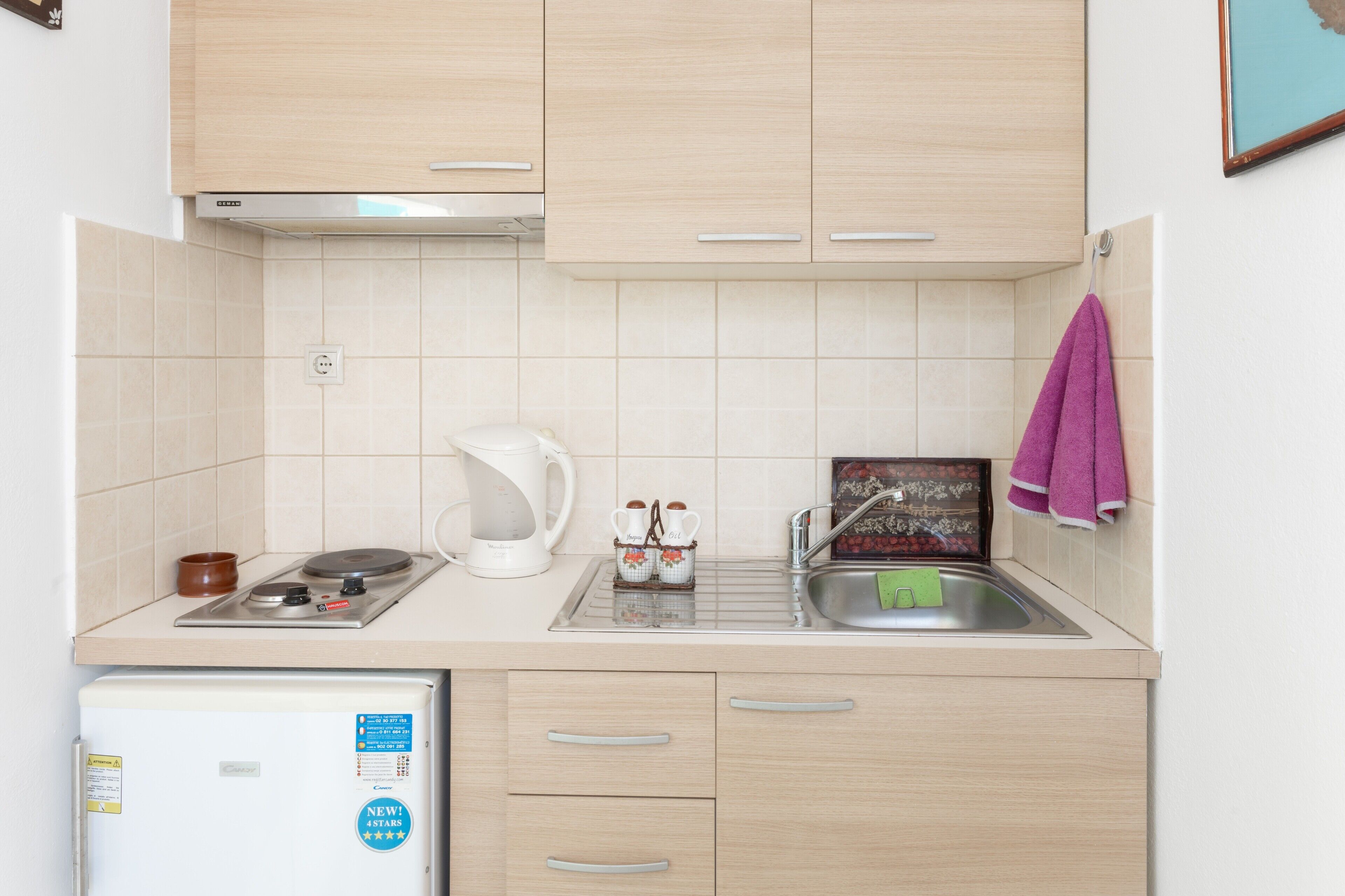 Una cocina equipada con cafetera, hervidor y un refrigerador pequeño.