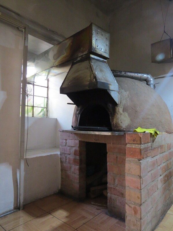 A brick-built outdoor pizza oven with a chimney, a window, and a tiled floor. - Hab. Family in Beautiful Colonial House in the Center of Cusco / Patio - 4 people (Cusco)