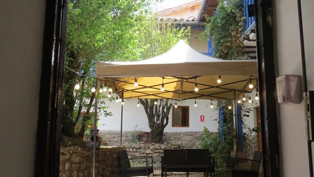 Un espacio de patio al aire libre con toldo, paredes de piedra y asientos.