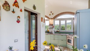 A kitchen with a stove, cabinets, and a window with a view. - Villa 'Paradiso' with Private Terrace, Private Garden and Wi-Fi (Castiglione della Pescaia)