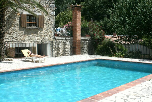 Une piscine avec un mur en pierre et une cheminée en briques.