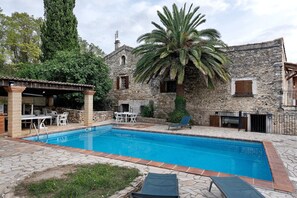 A stone building with a swimming pool, outdoor seating, and a palm tree. - Holiday Home 'La Maison De Yana' with Private Pool, Shared Terrace and Wi-Fi (Saint-Marcel-d'Ardèche)