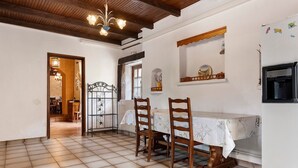 A dining area with a tiled floor, wooden chairs, a table with a white tablecloth, and a chandelier. - Holiday Home 'La Maison De Yana' with Private Pool, Shared Terrace and Wi-Fi (Saint-Marcel-d'Ardèche)