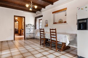 A dining area with a tiled floor, wooden chairs, a table with a white tablecloth, and a chandelier. - Holiday Home 'La Maison De Yana' with Private Pool, Shared Terrace and Wi-Fi (Saint-Marcel-d'Ardèche)
