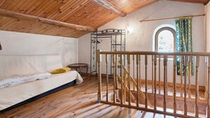 A room with a wooden ceiling, a bed, a small table, a metal rack, and a staircase with wooden railings. - Holiday Home 'La Maison De Yana' with Private Pool, Shared Terrace and Wi-Fi (Saint-Marcel-d'Ardèche)