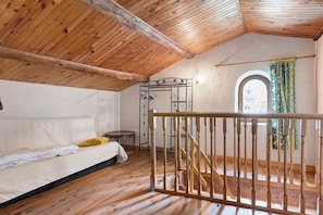 A room with a wooden ceiling, a bed, a small table, a metal rack, and a staircase with wooden railings. - Holiday Home 'La Maison De Yana' with Private Pool, Shared Terrace and Wi-Fi (Saint-Marcel-d'Ardèche)