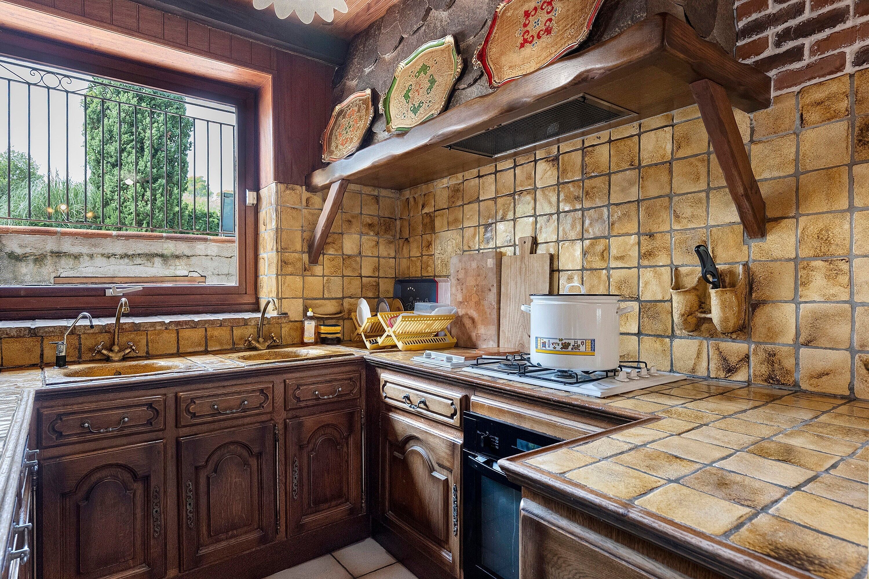 A kitchen with a stone backsplash, wooden cabinets, a sink, and a stove.