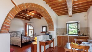 Una habitación con cama, mesa, microondas, lavamanos y ventana.