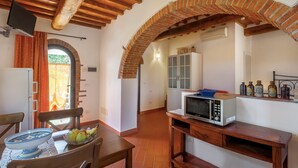 Una cocina con microondas, mesa de madera y frutero.