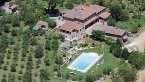 Une vue aérienne d’un vaste domaine comprenant plusieurs bâtiments, une piscine et de nombreux espaces verts.