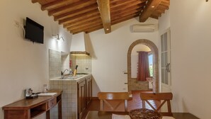 Une cuisine avec un plafond en bois, un téléviseur fixé au mur, un pare-feu en carrelage et une fenêtre avec un rideau.