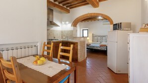 A kitchen with a dining table, chairs, a refrigerator, and a microwave. - Podere Papèra - 'Volpe Flat' Apartment with Mountain View, Wi-Fi and Air Conditioning (San Casciano in Val di Pesa)