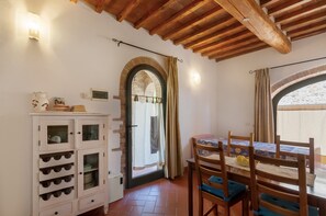 Un coin repas comprenant une table, des chaises, un buffet avec des verres à vin et une vue à travers une fenêtre en arc de cercle.