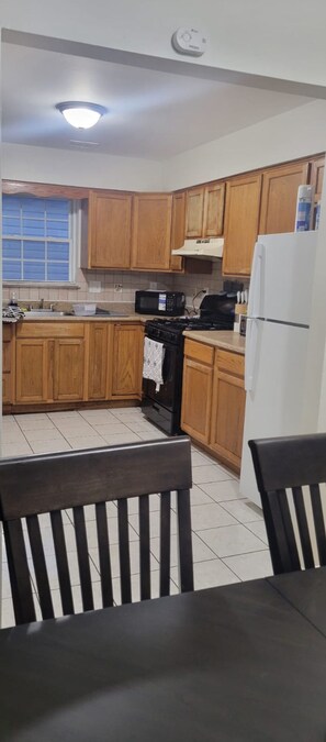 A kitchen with wooden cabinets, a stove, a microwave, and a refrigerator.