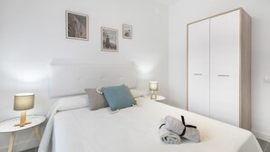 Una cama bien hecha con almohadas, una lámpara de noche y un armario en una habitación minimalista.