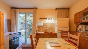A compact kitchen with a dining table, wooden cabinets, a built-in oven, and a refrigerator.