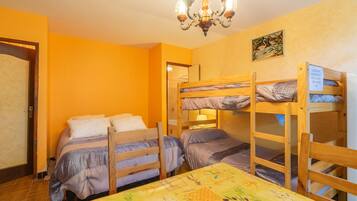 A room with bunk beds, a chandelier, and a table with a floral tablecloth.