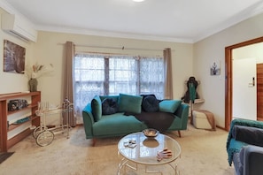 Ein Wohnzimmer mit einem grünen Sofa, einem Glastisch und einem Bücherregal.