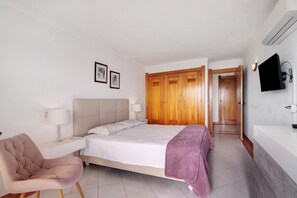 A bedroom with a bed, bedside table, chair, wardrobe, and a TV. - Apartment 'Apartamento Varandas Do Mar' with Sea View, Wi-Fi and Air Conditioning (Albufeira)