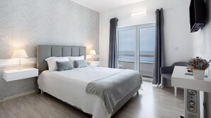 Una moderna camera d'albergo con un letto grande, lampade sui comodini, una scrivania e una TV.