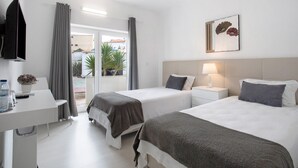 Une chambre d’hôtel avec deux lits, un bureau, une télévision et une fenêtre avec des rideaux.