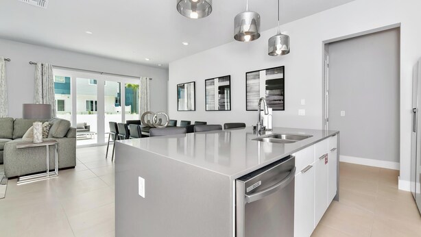 A modern kitchen with a central island, stainless steel appliances, and pendant lighting. - Modern, Luxury 1st Floor Condo Near Disney (Reunion)