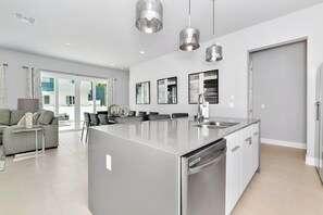 A modern kitchen with a central island, stainless steel appliances, and pendant lighting. - Modern, Luxury 1st Floor Condo Near Disney (Reunion)