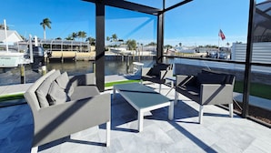 Un espace extérieur moderne, aménagé pour se détendre, avec vue sur un port de plaisance et des bateaux.