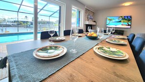 A dining area with a view of a swimming pool, a television, and a fireplace. - ⚓Sandys Coral Retreat! Canal Front, Pool, Hot Tub & More⚓ (Bradenton)